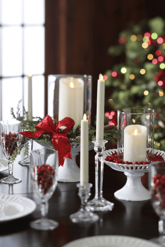 Christmas centerpiece ideas with candles, greenery, candle stands, taper candle holders, red berries