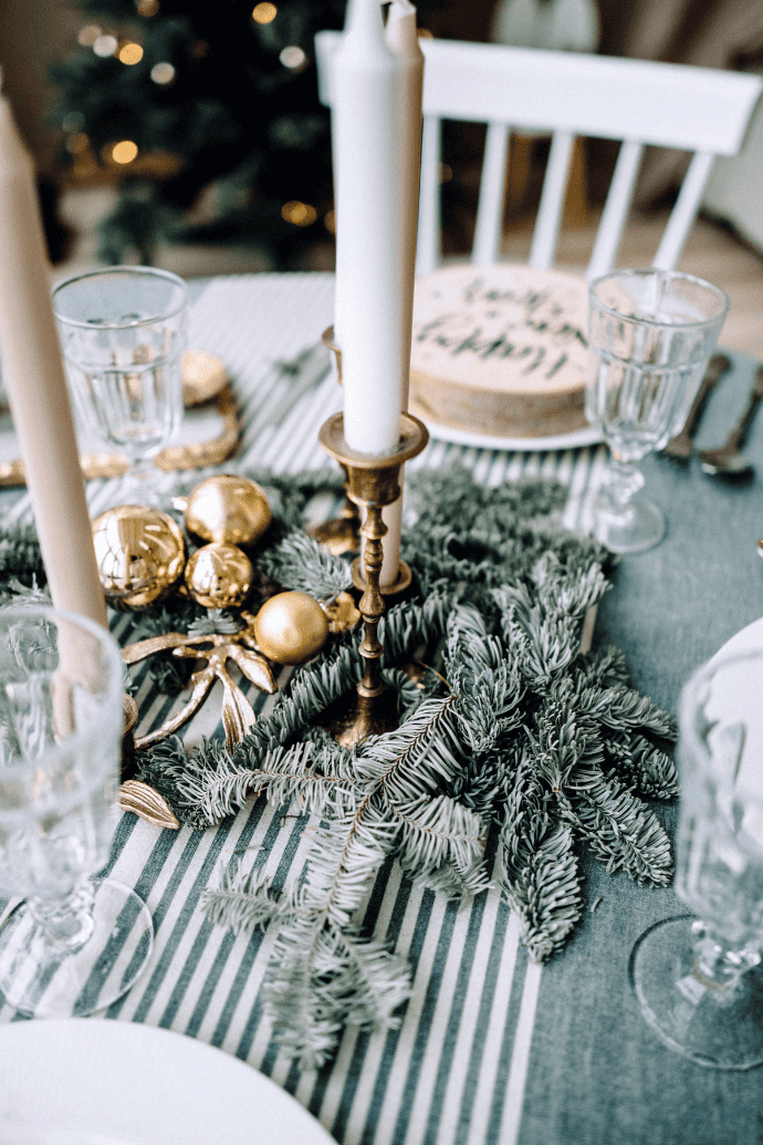 Christmas centerpiece ideas with candles, greenery, taper candle holders, gold ornaments