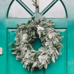 Wreath with winter greenery hanging from a teal front door