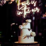 love is in the air wedding neon sign with cake, flowers, arch