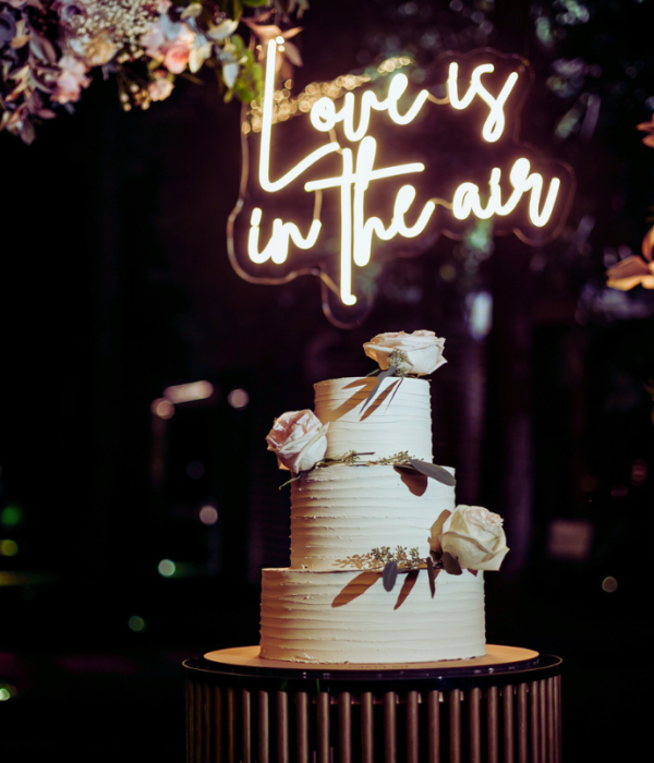 love is in the air wedding neon sign with cake, flowers, arch