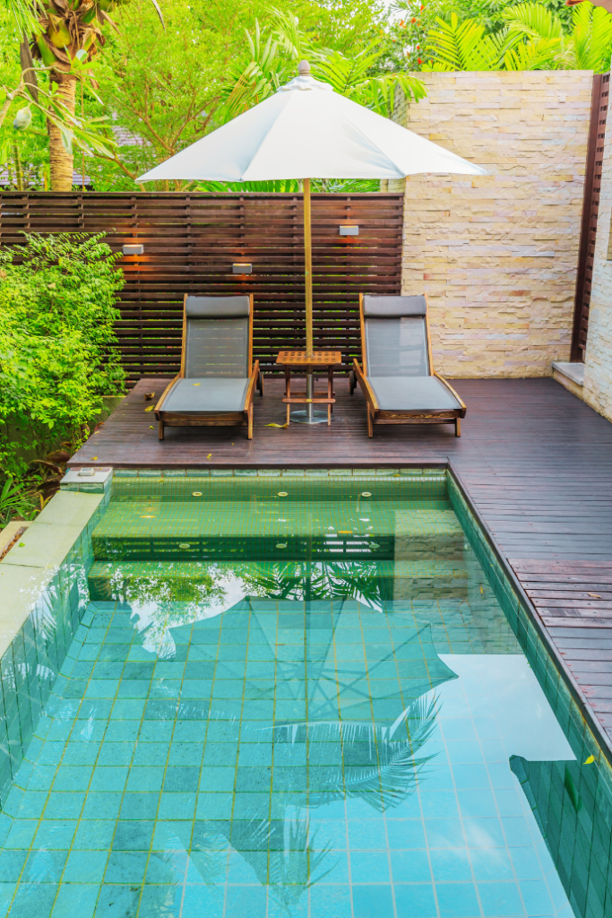 lounge chairs, table, umbrella on small pool deck, landscaping